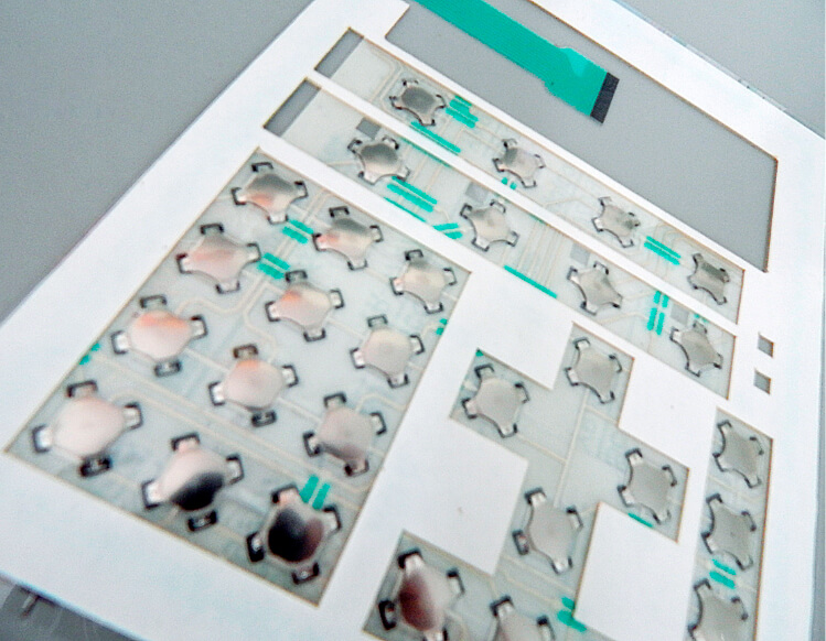 Detalhe do circuito flexível pronto para aplicação em teclado de membrana, impresso em poliéster, é possível visualizar as trilhas, máscara de proteção e calotas com feedback tátil.